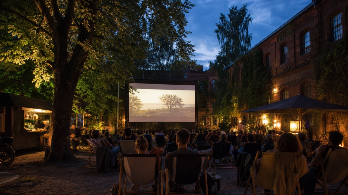 Illustration of a summer open-air cinema evening in a leafy Kreuzberg courtyard